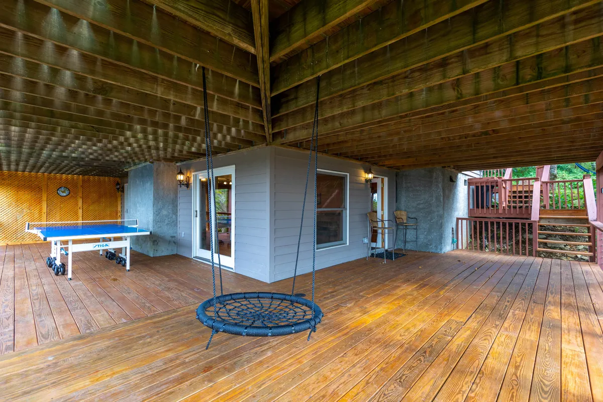 This exterior image features a welcoming area with a swing chair, ping pong table, and visible entrance to a room. It conveys a playful and communal atmosphere, suggesting spaces for both relaxation and active recreation. The ping pong table and swing provide elements that appeal to all ages, reinforcing the idea of group fun.