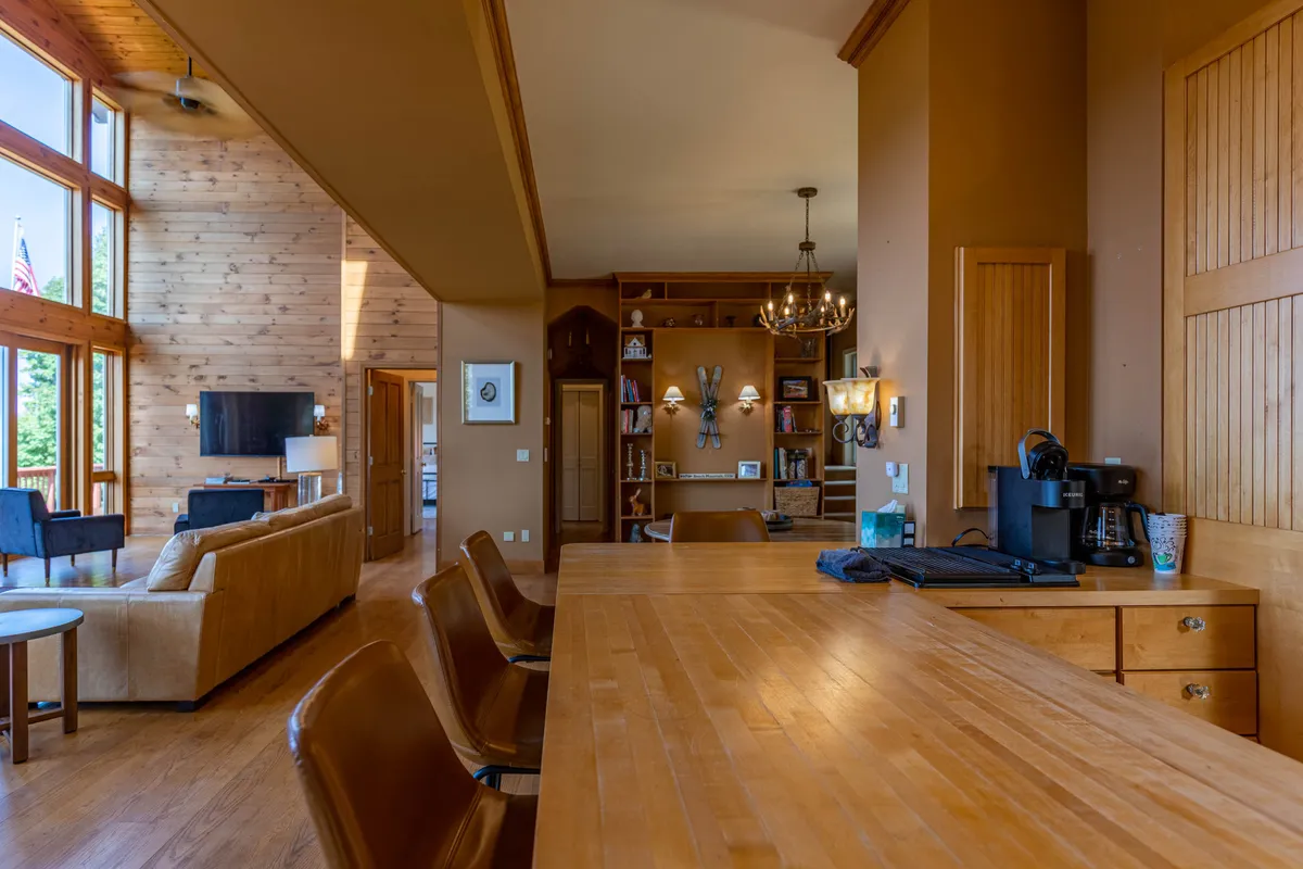 A stylish lounge area with a wooden bar, comfortable seating, a bookshelf, and expansive windows allowing sunlight to flood the space. The setup is ideal for enjoying drinks, reading, or simply relaxing with friends and family.